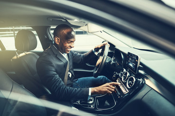 African businessman listening to music while driving through the