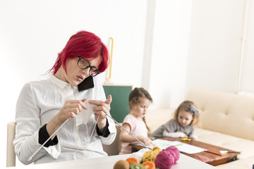 Mother Busy Knitting as Children Draw Art in the Background