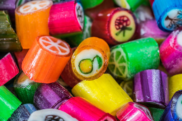 Colorful candy sweets close up, selective focus. Different tastes and drawings of fruits on candies, apricot taste in front, made in prague