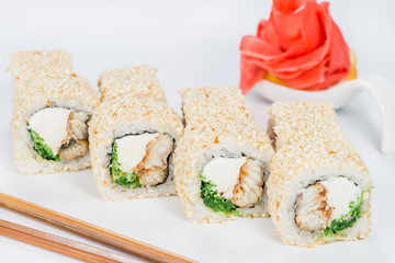 Delicious sushi rolls with rice, cream cheese, cucumber and sesame seeds on light background
