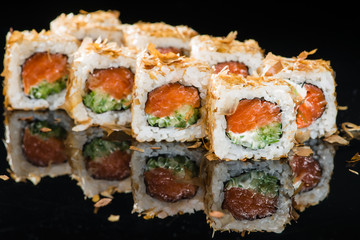 Traditional Japanese cuisine. Tasty sushi rolls with rice, cream cheese, salmon, cucumber and tuna on dark background