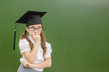 thoughtful girl in graduation cap looking away. Space for text