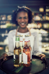 Friendly young African server carrying drinks in a restaurant
