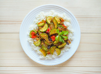 A plate of rice with vegetables on wooden background. Asian cuisine.

