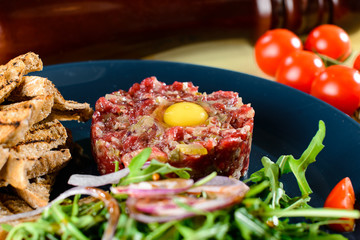 Dish with beef tartare, tomatoes and leaves in a restaurant, close-up