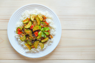 A plate of rice with vegetables on wooden background. Asian cuisine.

