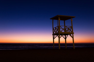 Lifeguard tower on empty beach at colorful sunset in La Serena, Chile. Nobody on calm, peaceful dusk by the sea