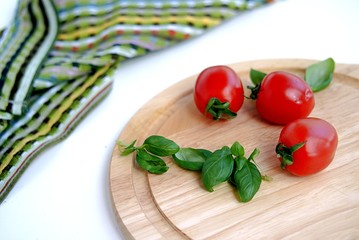 Ripe tomatoes and basil on a wooden board