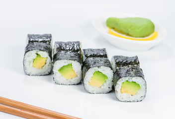 Fresh delicious Japanese sushi with avocado on light background