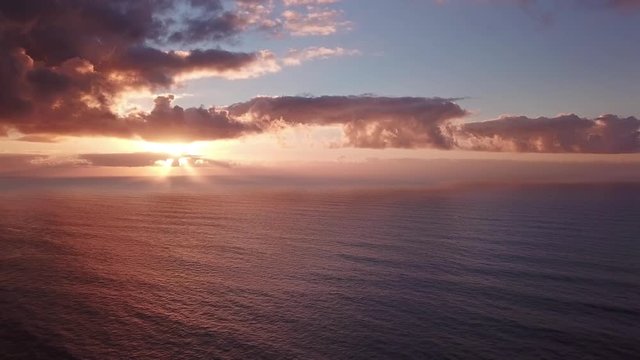 Flying to setting sun in dramatic clouds over Atlantic ocean, 4k