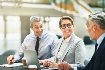 Mature office colleagues smiling and talking together during a m