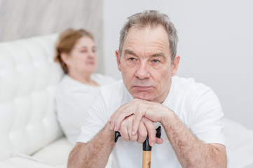 unhappy senior couple sitting on bed