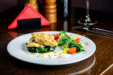 Delicious fish served with tomatoes, lemon and herbs on the wooden board. Top view, flat lay