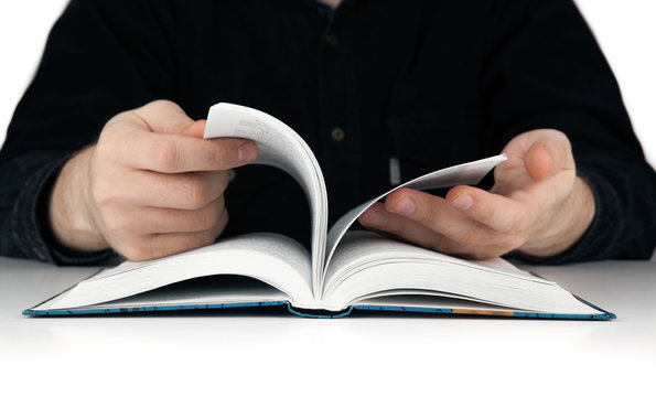 men's hands flipping through the pages of the book
