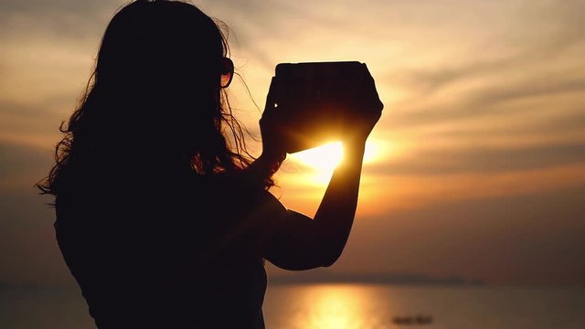 Girl takes selfie on mobile phone camera on beautiful sea view on the background with sunny lights reflected in the sea. slow motion. 1920x1080