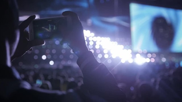 Close up of recording video with smartphone during a concert. Audience photo take macro