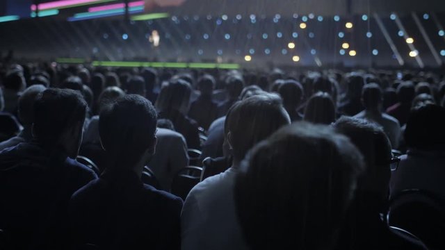 Spectators sit on seats in break of concert