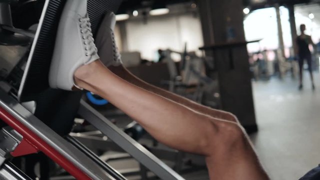 Man Using A Press Machine In A Fitness Club. Man doing an exercise on its legs in the simulator. side view close up macro closeup