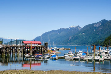 Boats in a Harbour along a Beautiful Bay Surrounded by Towering Forested Mountains on a Clear Summer Day. Horseshoe Bay, Vancouver, BC, Canada.