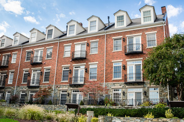 Fototapeta premium Red Wooden Front Door and a White Window with Black Shutters on an American Colonial House along a Brick Sidewalk. Alexandria, VA