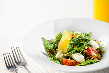 Tasty vegetarian salad with tomatoes, lettuce leaves, lemon and cheese in a plate