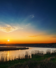 orange sunset in dark blue sky over river