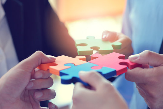 Group of business people assembling jigsaw puzzle and represent team support and help concept
