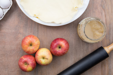 apples with applesauce next to a dough to make an apple pie top view
