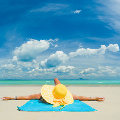 Fototapeta na wymiar Woman in bikini wearing a yellow hat at tropical beach