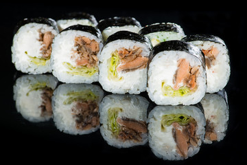 Japanese cuisine. Appetizing maki sushi rolls with rice, avocado, cucumber and shrimp on dark background