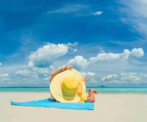 Woman in bikini wearing a yellow hat at tropical beach