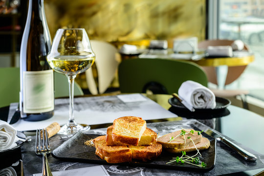 Tasty foie Gras with toasts and glass of white wine at a restaurant