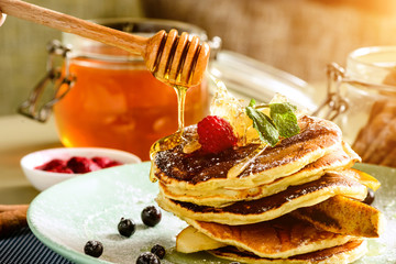 Process of preparing sweet delicious pancake blinis with jam and berries in the plate in rays of...