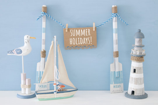 nautical concept with wooden decorative boat oars and hanging note message on a string next to lighthouse, seagull and boat over blue background.