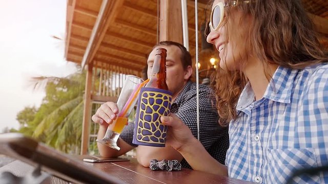 Beautiful romantic dinner on the beach cafe couple on honeymoon drinking fruit cocktails and beer near the sea. slow motion. 1920x1080