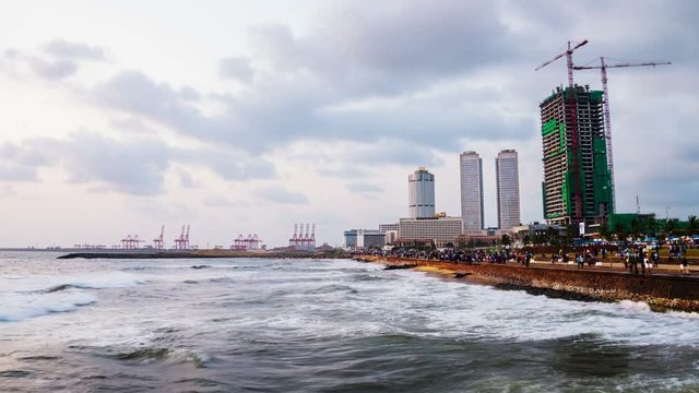 Colombo, Sri Lanka. Cityscape of Colombo, Sri Lanka with modern buildings at sunset. Ocean waves at night and cloudy sky. People at promenade area. Time-lapse at sunset