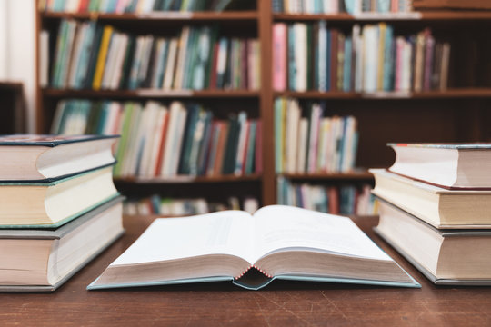 Education learning concept with opening book or textbook in old library, Book in library with old open textbook, Stack piles of literature text academic archive on reading desk in school class room