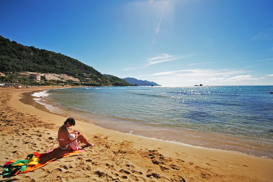 mother breastfeeding a child on the beach