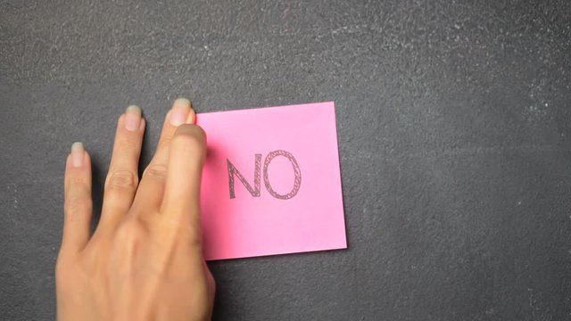 Closeup woman's hand sticking note with No word on the blackboard - video in slow motion
