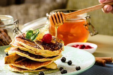 Process of preparing sweet delicious pancake blinis with jam and berries in the plate