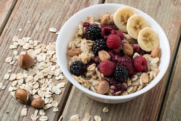 oatmeal with fruit, banana and hazelnuts on a wooden table