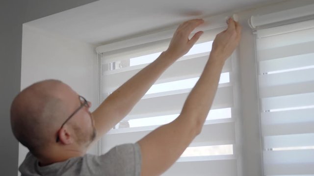 Close up shot of a man installing new blinds on his window in apartment.