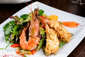 Romantic dinner at a restaurant. Delicious prepared shrimp with tomatoes, sauce and basil leaves.