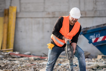 Male construction worker using a jackhammer on construction site