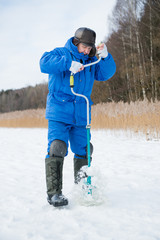 Fototapeta na wymiar Firsheman catching fish on a lake at winter cold day