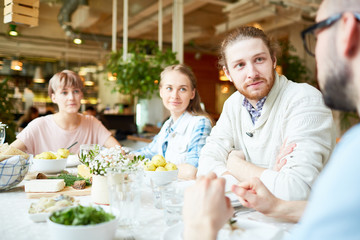 Three people listening to their friend story by dinner while having rest in cafe