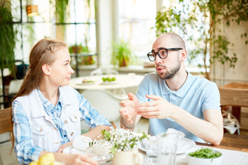 Young man voicing his plans and ideas to his girlfriend by dinner or date in cafe