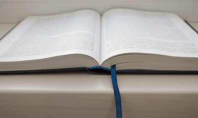 Open blue book with book marker on white wooden table. Education and learning concept. Literature background. Religious book. Information and knowledge concept. School and wisdom concept.