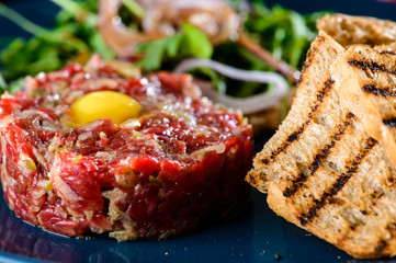 Dish with beef tartare, tomatoes and leaves in a restaurant, close-up
