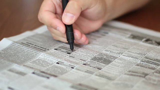 man highlighting the advertisements in newspaper with marker
